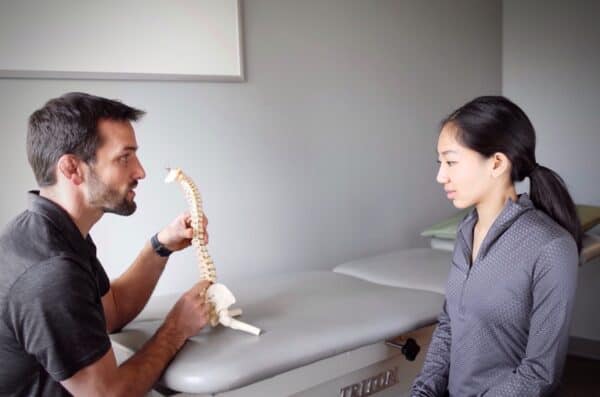 Spine-Recovery Olympian and doctor of physical therapy Matt Gentry teaching client about the mechanics of the spine during an examination and first visit.