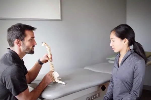 Olympian and doctor of physical therapy Matt Gentry teaching client about the mechanics of the spine during an examination and first visit.